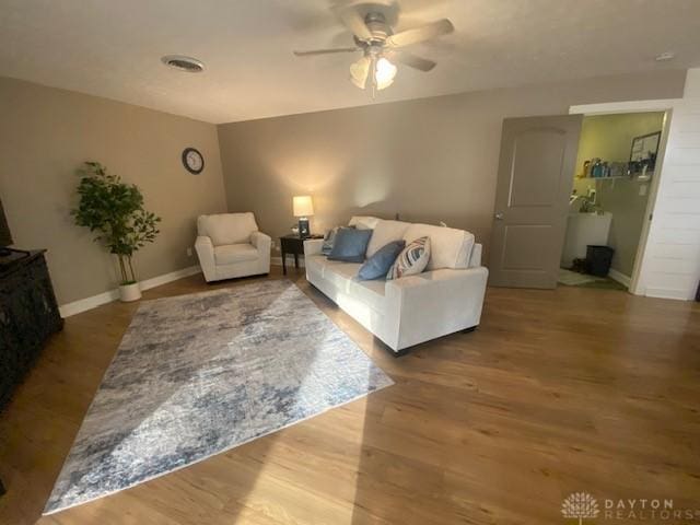 living area featuring a ceiling fan, visible vents, wood finished floors, and baseboards