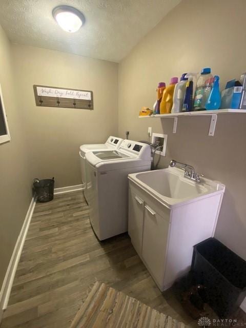 clothes washing area with baseboards, laundry area, light wood-style flooring, a sink, and washer and clothes dryer