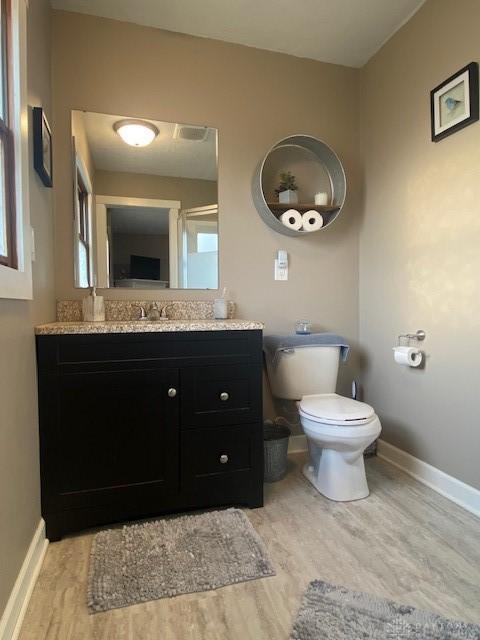 bathroom featuring vanity, toilet, wood finished floors, and baseboards