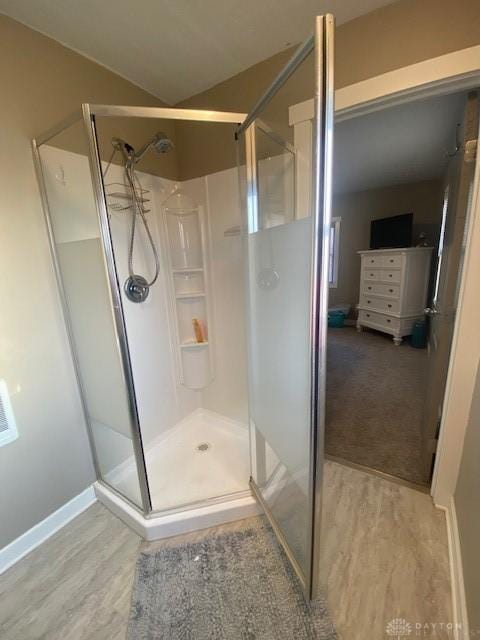 bathroom featuring lofted ceiling, wood finished floors, and a stall shower