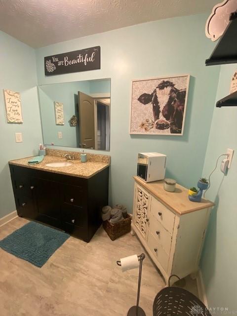 bathroom featuring a textured ceiling, vanity, and baseboards