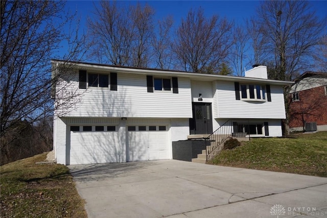 bi-level home featuring brick siding, an attached garage, concrete driveway, and a chimney