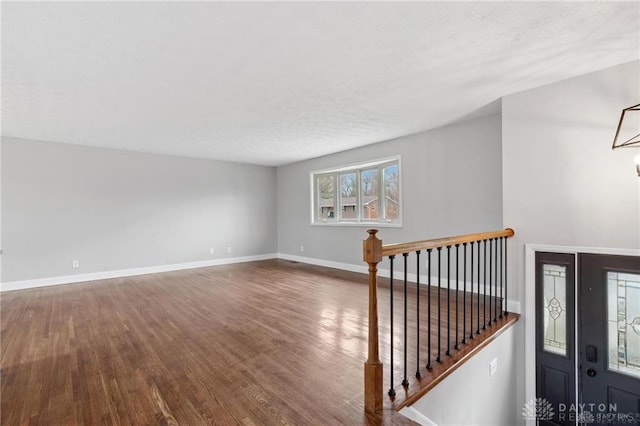 interior space featuring baseboards, a textured ceiling, an inviting chandelier, and wood finished floors