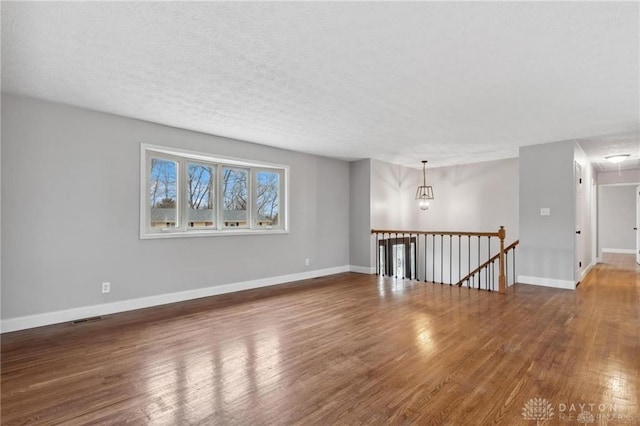 spare room featuring visible vents, baseboards, attic access, wood finished floors, and a textured ceiling