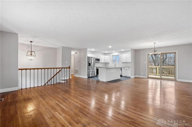 unfurnished living room featuring dark wood finished floors, visible vents, and an inviting chandelier