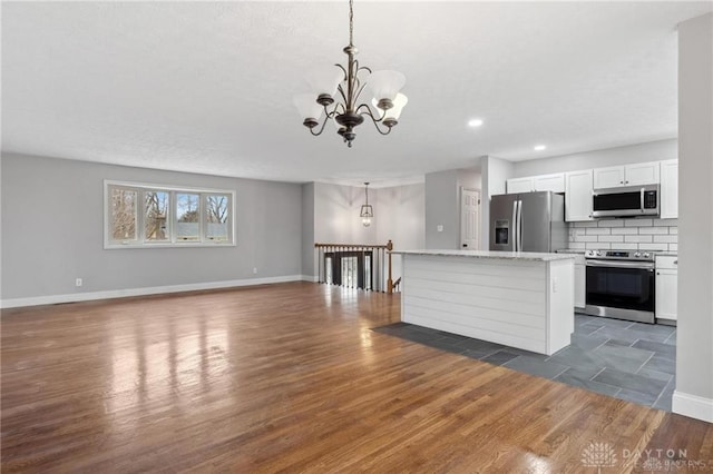 kitchen with tasteful backsplash, dark wood-type flooring, a chandelier, stainless steel appliances, and white cabinetry