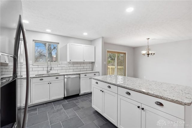 kitchen featuring backsplash, light stone countertops, stainless steel appliances, white cabinetry, and a sink