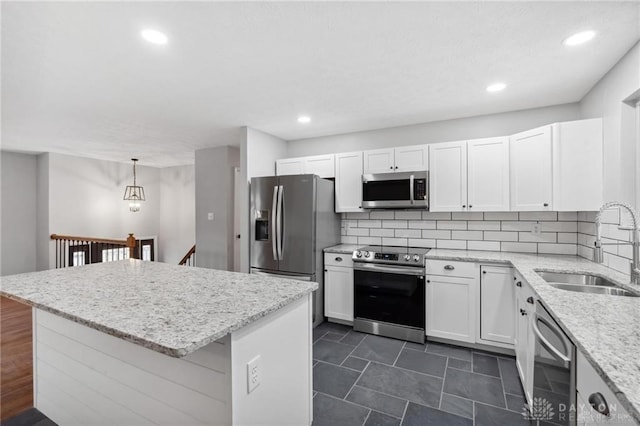 kitchen featuring a kitchen island, decorative backsplash, appliances with stainless steel finishes, white cabinets, and a sink