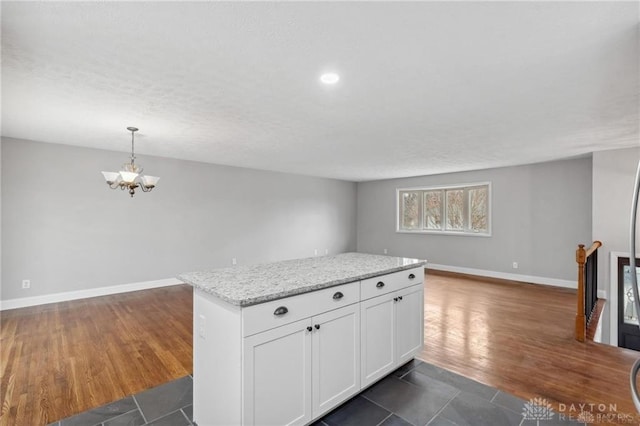 kitchen with dark wood-type flooring, baseboards, open floor plan, an inviting chandelier, and white cabinetry