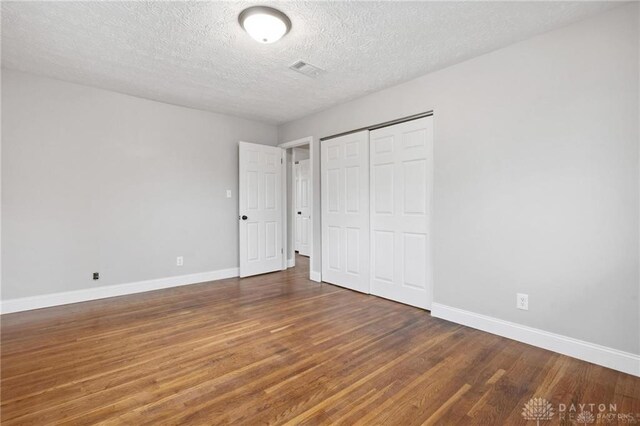 unfurnished bedroom featuring wood finished floors, baseboards, and a closet