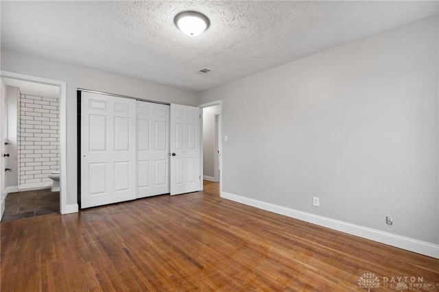 unfurnished bedroom featuring wood finished floors, a closet, and baseboards