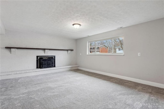 unfurnished living room featuring carpet, visible vents, baseboards, a fireplace, and a textured ceiling