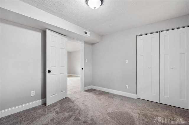 unfurnished bedroom featuring a closet, carpet flooring, a textured ceiling, and baseboards