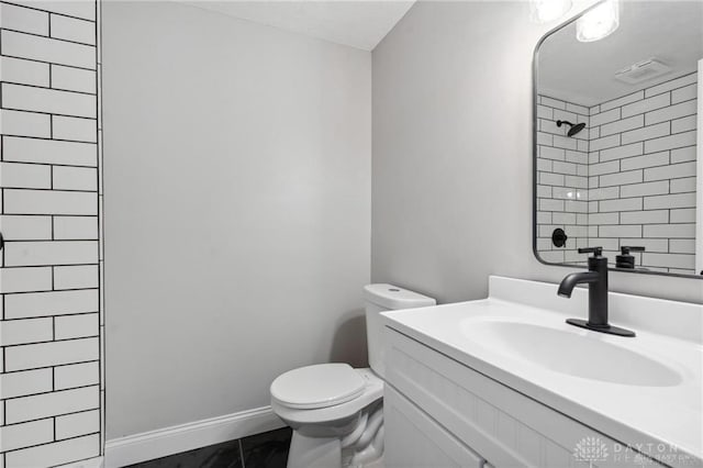 full bathroom featuring visible vents, toilet, tiled shower, baseboards, and vanity