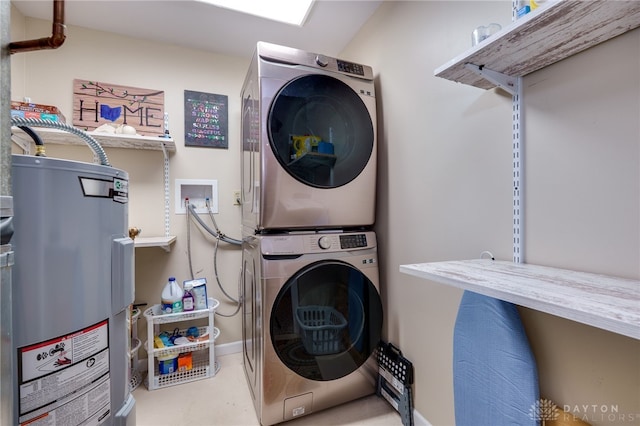 laundry area featuring laundry area, electric water heater, and stacked washing maching and dryer