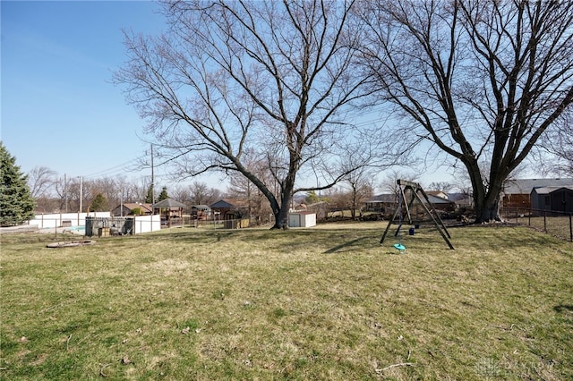 view of yard with an outdoor structure, a playground, fence, and a shed