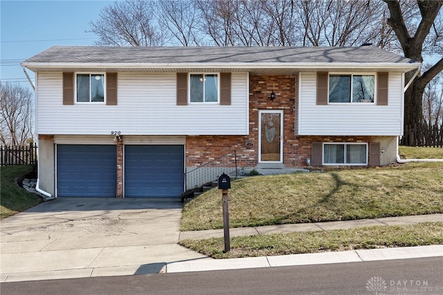 bi-level home with a front yard, an attached garage, brick siding, and driveway