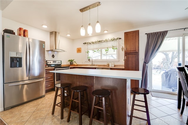 kitchen with light tile patterned floors, wall chimney exhaust hood, appliances with stainless steel finishes, and a sink