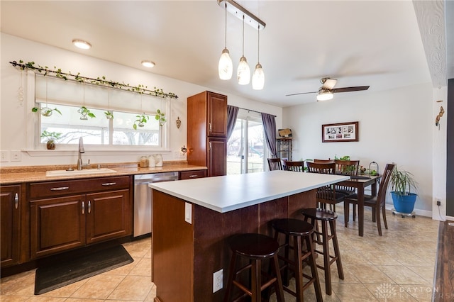 kitchen with stainless steel dishwasher, light countertops, a breakfast bar area, and a sink