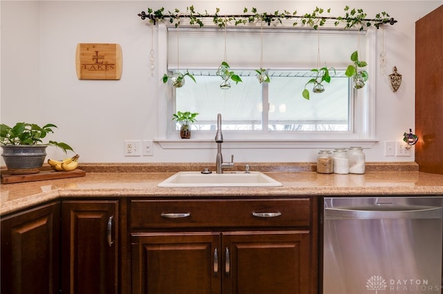 kitchen featuring dark brown cabinetry, a sink, light countertops, and stainless steel dishwasher