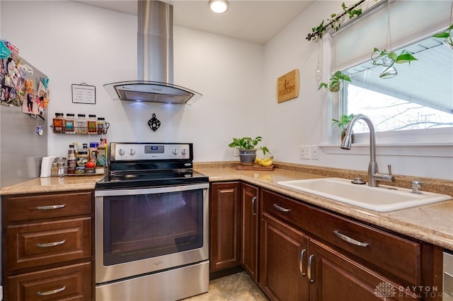 kitchen with stainless steel electric range oven, light tile patterned floors, a sink, light countertops, and island range hood