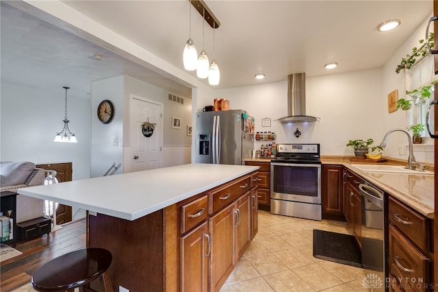 kitchen with visible vents, a sink, wall chimney range hood, appliances with stainless steel finishes, and light countertops