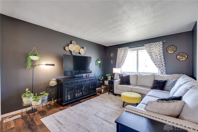 living room with wood finished floors, visible vents, and baseboards