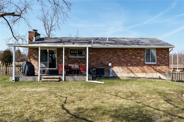 back of property featuring fence, a yard, brick siding, a chimney, and a patio area