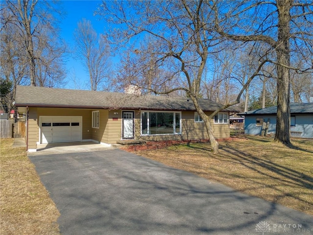 ranch-style house with aphalt driveway, an attached garage, fence, and a front lawn