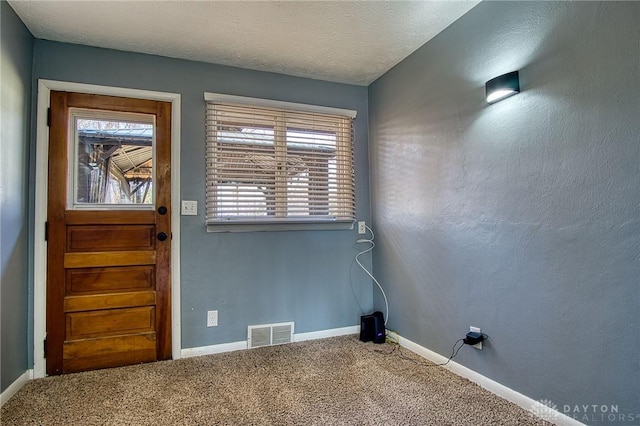 doorway to outside featuring a textured ceiling, carpet, visible vents, and baseboards