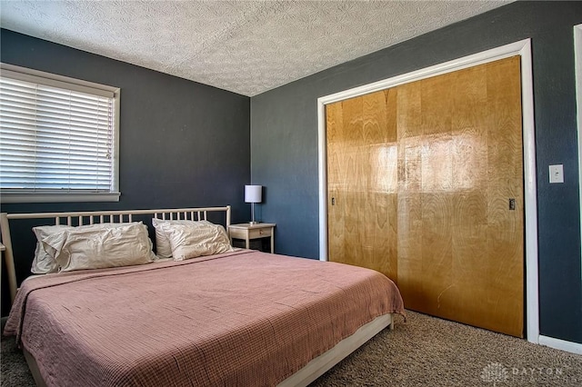 bedroom with a closet, carpet floors, and a textured ceiling