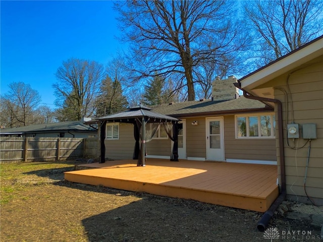 exterior space with a gazebo, a wooden deck, a chimney, and fence