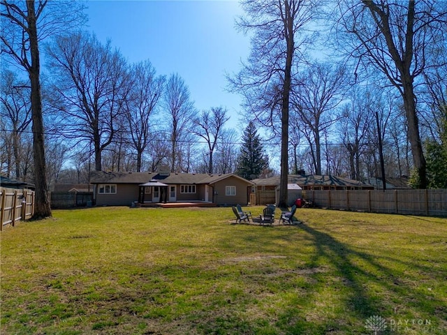 exterior space featuring a deck, a fenced backyard, a lawn, and an outdoor fire pit