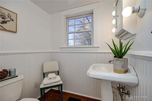 bathroom with a wainscoted wall, toilet, and wood finished floors