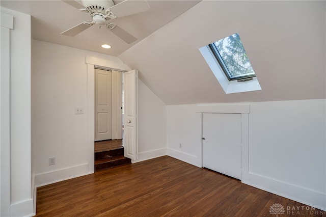 additional living space with lofted ceiling with skylight, dark wood-type flooring, recessed lighting, baseboards, and ceiling fan