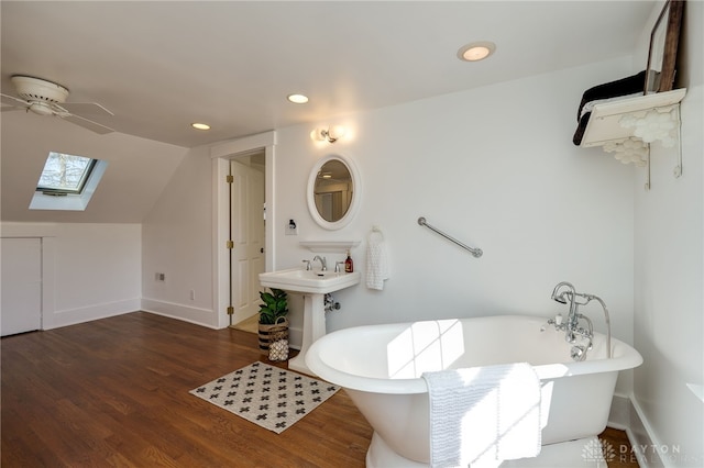 bathroom featuring lofted ceiling with skylight, a freestanding bath, a ceiling fan, and wood finished floors