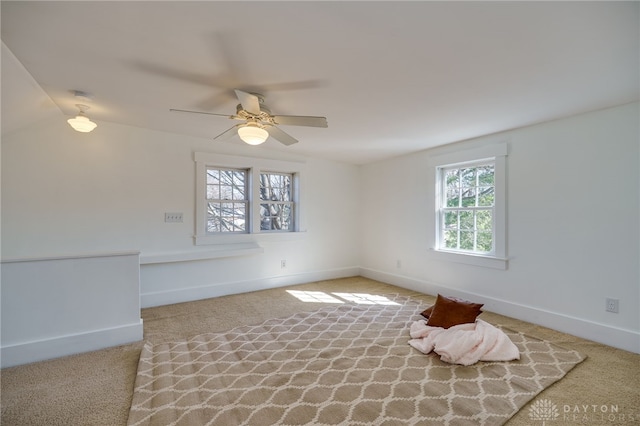 carpeted empty room with ceiling fan and baseboards