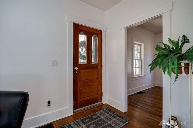 foyer entrance featuring visible vents, baseboards, and dark wood finished floors