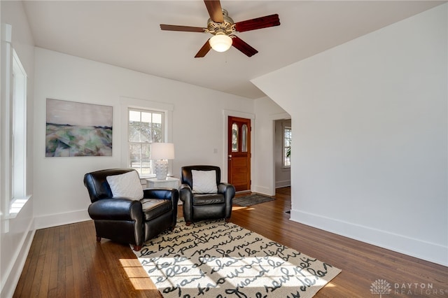 living area with a ceiling fan, wood finished floors, and baseboards