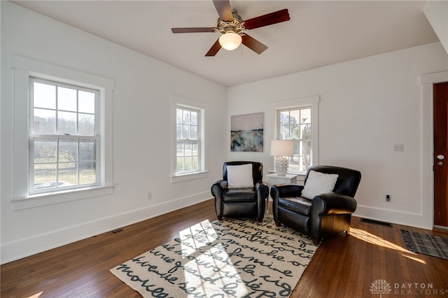 living area featuring visible vents, baseboards, hardwood / wood-style floors, and a ceiling fan