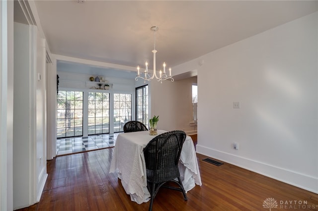 dining area with dark wood-style floors, visible vents, baseboards, and an inviting chandelier