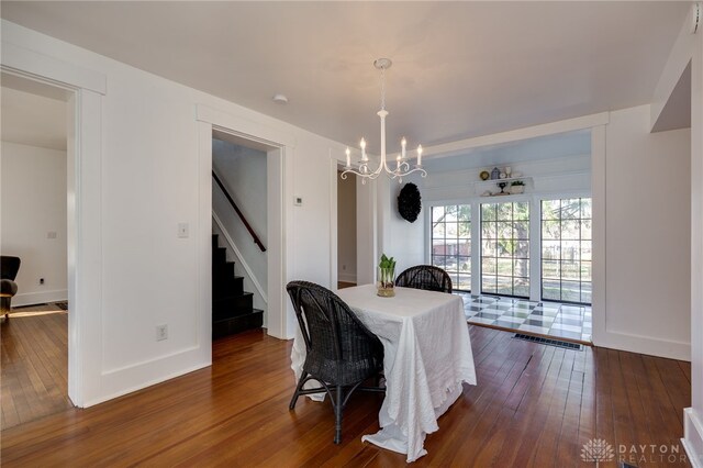 dining room featuring visible vents, stairway, baseboards, a chandelier, and dark wood-style flooring