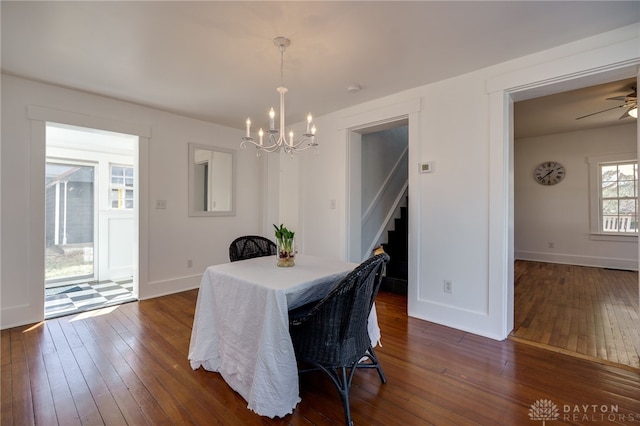 dining space with stairway, baseboards, dark wood-type flooring, and ceiling fan with notable chandelier