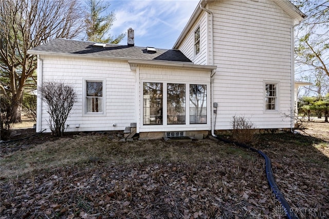 back of property with a chimney and a shingled roof