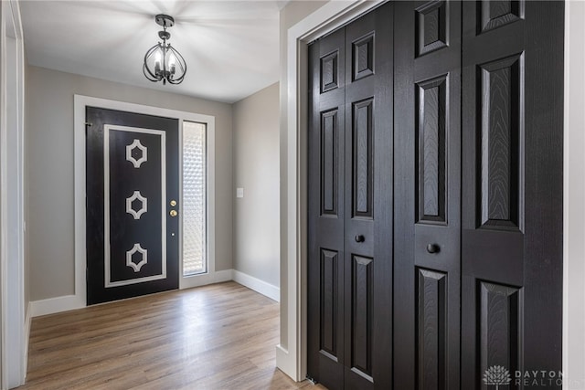 entrance foyer with wood finished floors, baseboards, and a chandelier