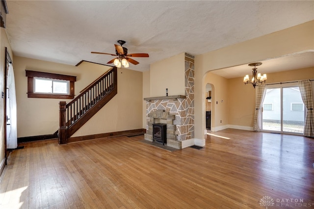 unfurnished living room featuring baseboards, hardwood / wood-style floors, stairs, and ceiling fan with notable chandelier