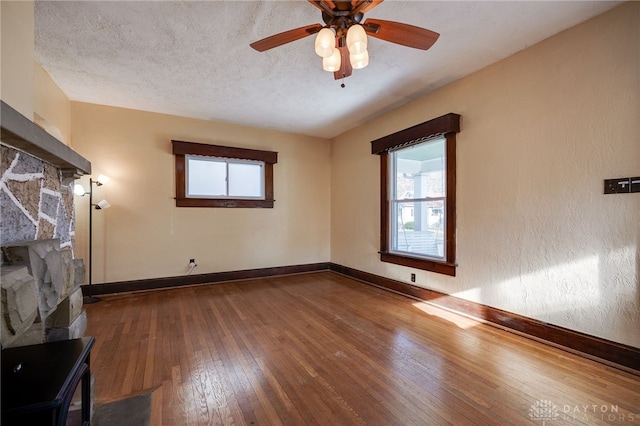 spare room featuring a wealth of natural light, a textured ceiling, baseboards, and hardwood / wood-style floors