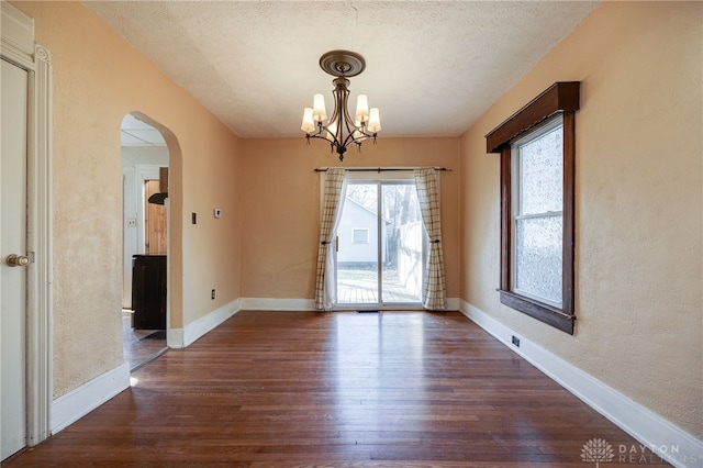 unfurnished dining area with dark wood-type flooring, baseboards, and arched walkways