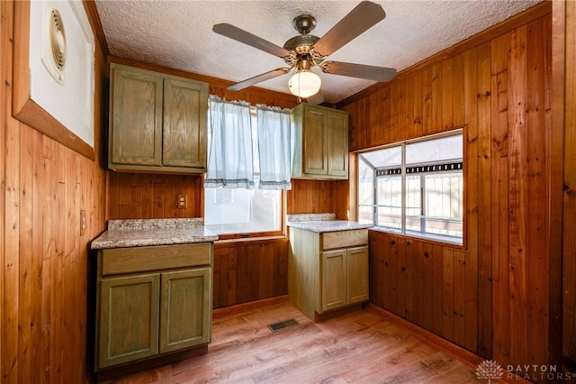 kitchen featuring wooden walls, ceiling fan, light countertops, a textured ceiling, and light wood-type flooring