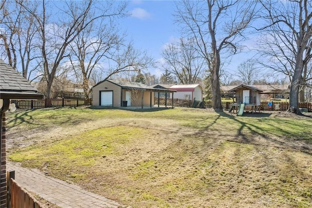 view of yard featuring a garage, an outbuilding, and fence